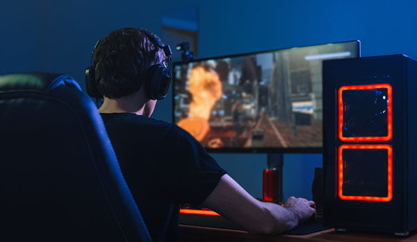 Gamer young man playing online immersive gamer, view over his shoulder