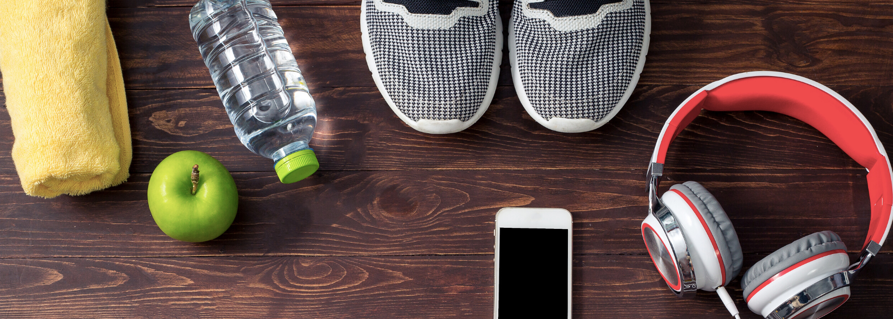 a collection of workout accessories, bottle of water, apple, ipod, headphones, running shoes