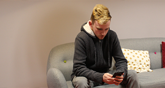 serviceresthumb Picture of a young man sitting down looking at his phone