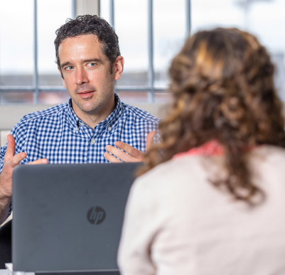 Man talking to woman from behind laptop