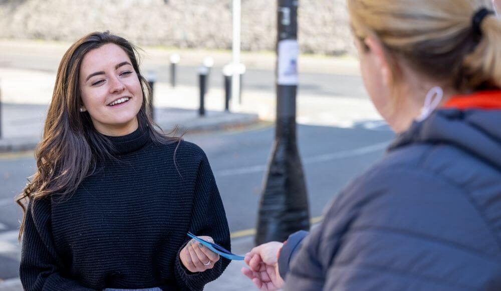 Young woman talking to older woman who is handing her a brochure