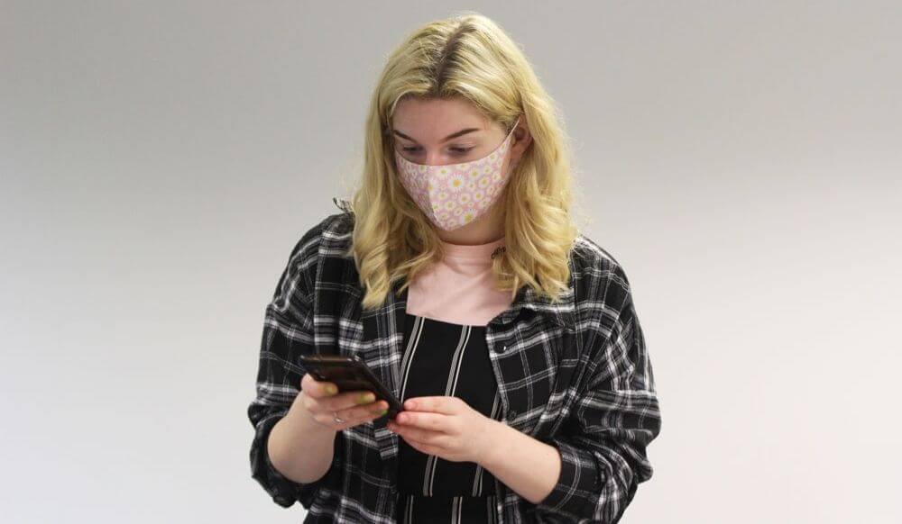 Different levels of mental health Young woman wearing a mask looking at her mobile phone
