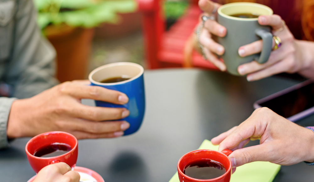 close up of four people holding mugs of coffee