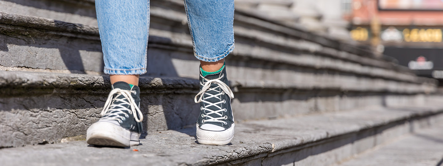 feet wearing converse walking along old grey steps