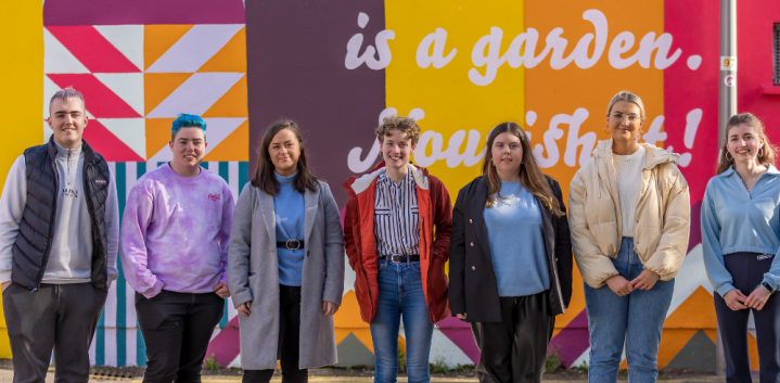 group of young people standing against colourful backdrop